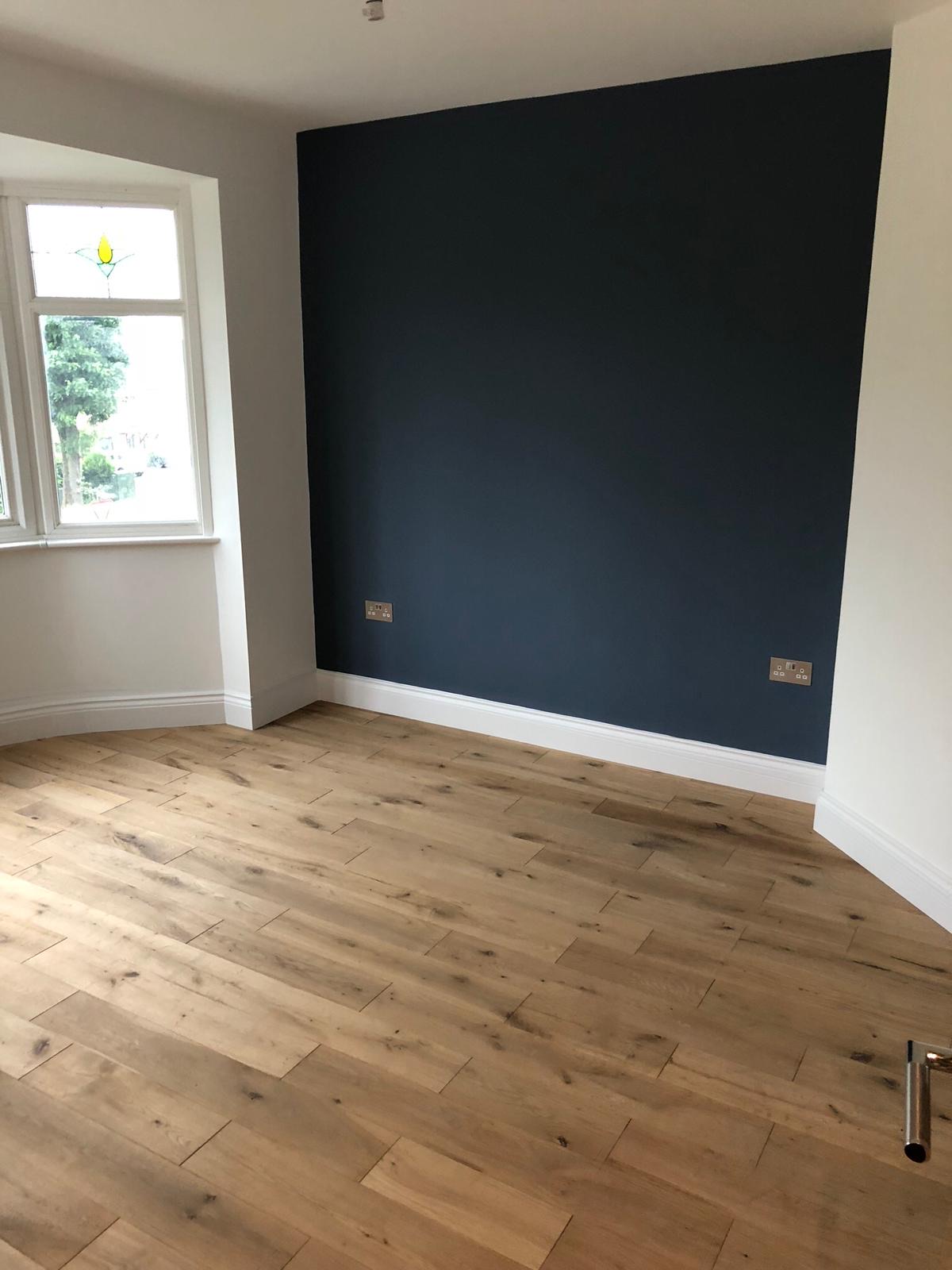 Room with dark accent wall and oak flooring